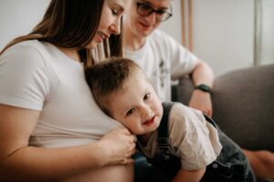 chlapeček se opírá o maminku a její těhotenské bříško